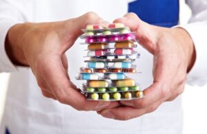 A healthcare worker holds a pile of pill packages